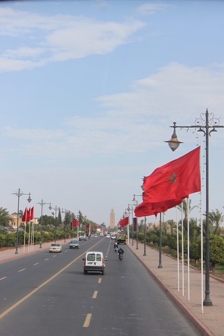 Avenida com bandeira de Marrocos e Koutoubia ao longe ©Viaje Comigo