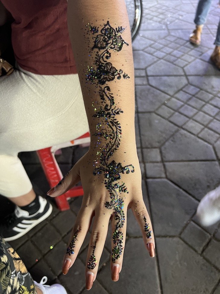 Artista aplicando tatuagem de henna mehndi na mão feminina